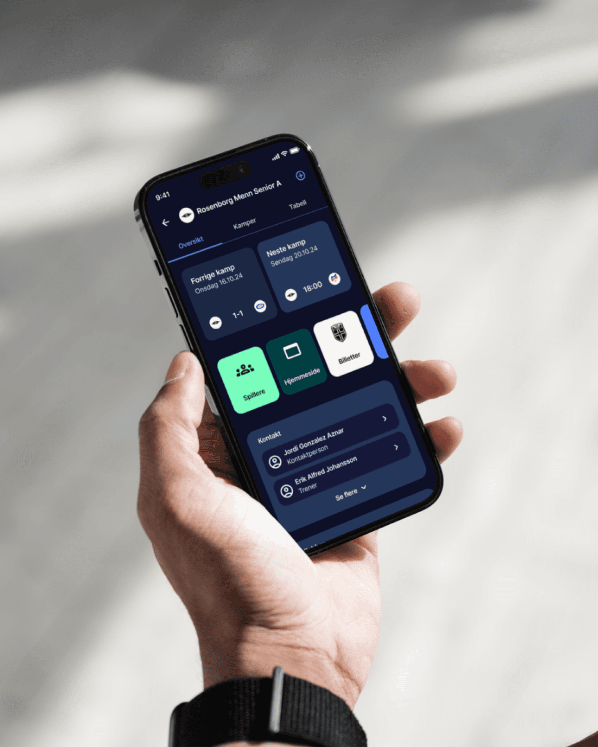 Hand holding smartphone with Rosenborg football team app showing match schedule, tickets and player info.