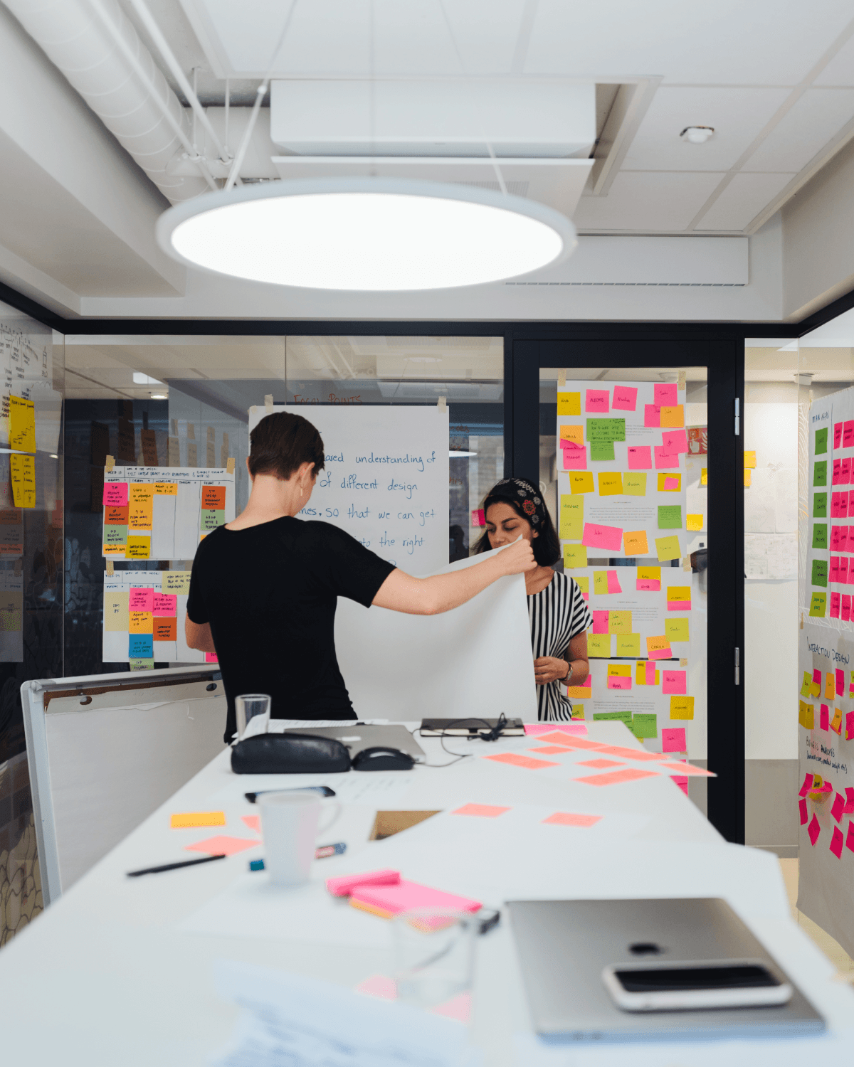 Team workshop in a modern office, with people brainstorming using sticky notes and whiteboards.